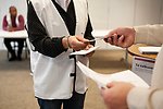 En röstmottagare som delar ut valkuvert till en väljare. 